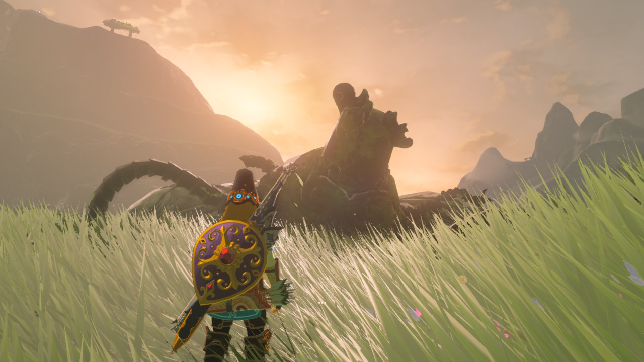 A screenshot from Breath of the Wild showing Link with heavily decorated equipment, regarding a shattered pottery-like beast in front of a golden sunset.