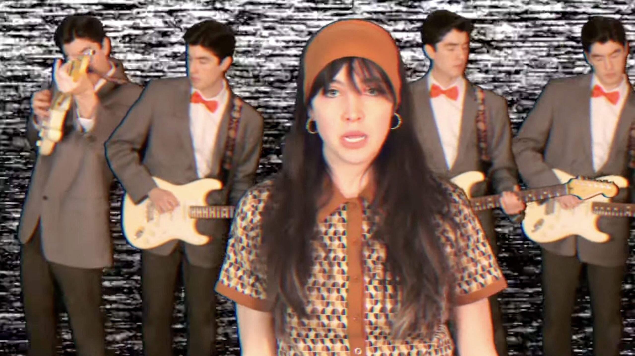 Screenshot from the CQ Lucius music video "You're the Noise," showing CQ singing in the foreground while four copies of her brother Schaeffer play guitar behind her, over a background of monochrome static.